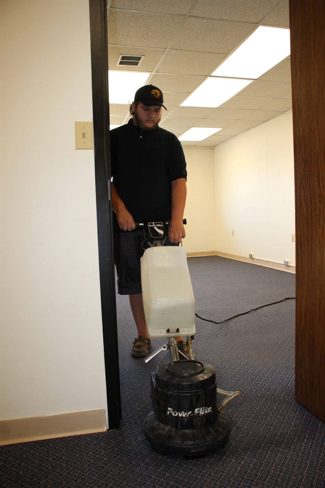 A rotary floor machine being run across an office carpet.